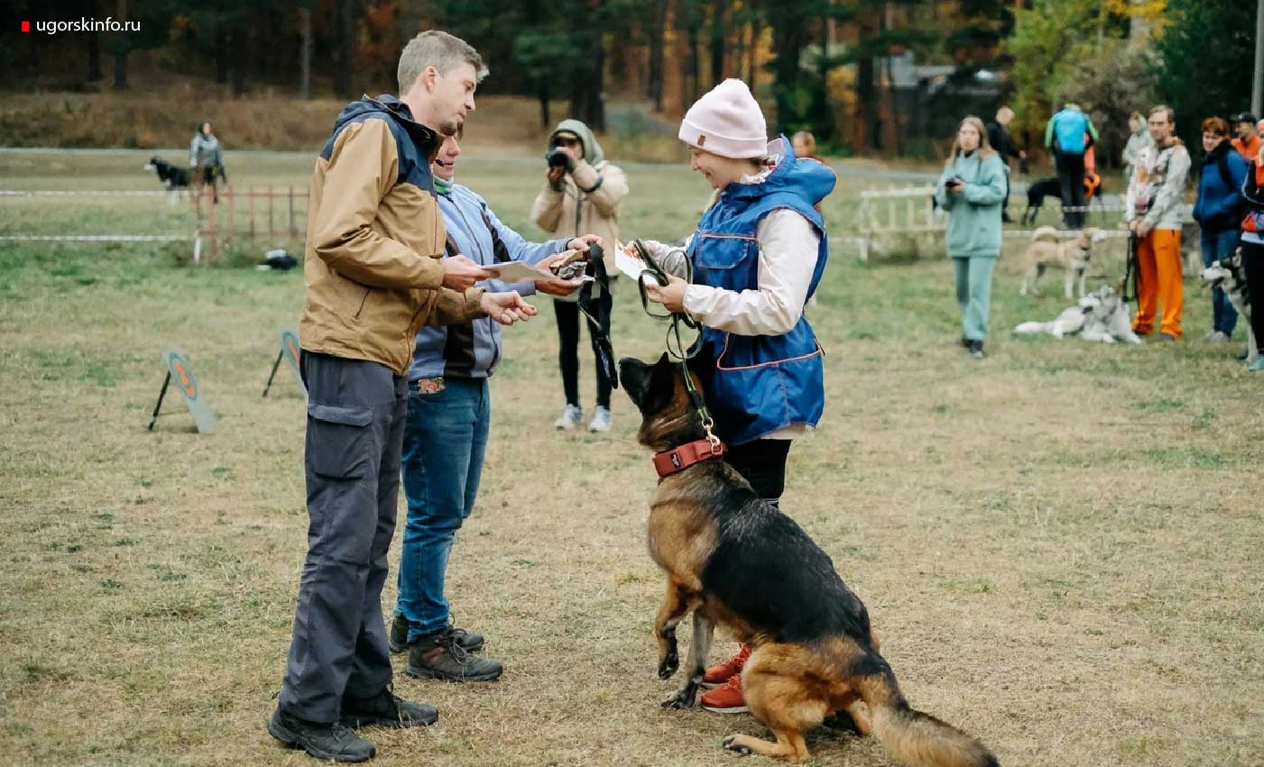 На фото Мария Белоконь со своей немецкой овчаркой по кличке Кира получают награду за успешно пройденные соревнования по каникроссу.